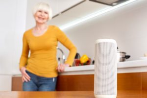 Image of a senior resident in the kitchen with a speaker on a table.