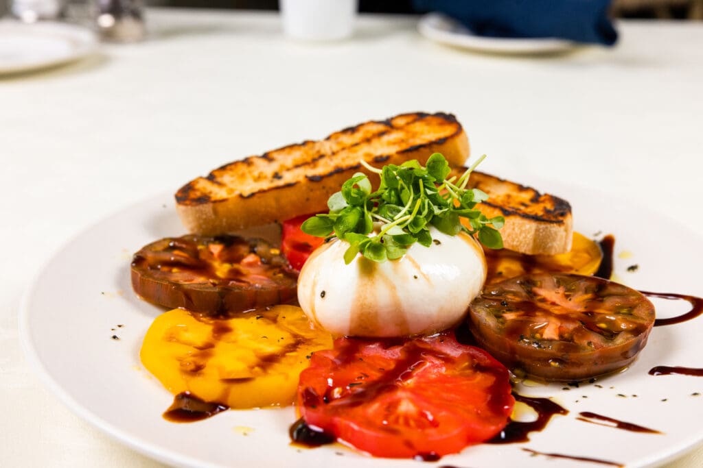 A meal with heirloom tomatoes, burrata, and toasted bread, showcasing resident's favorite meals at Essex Meadows in CT.