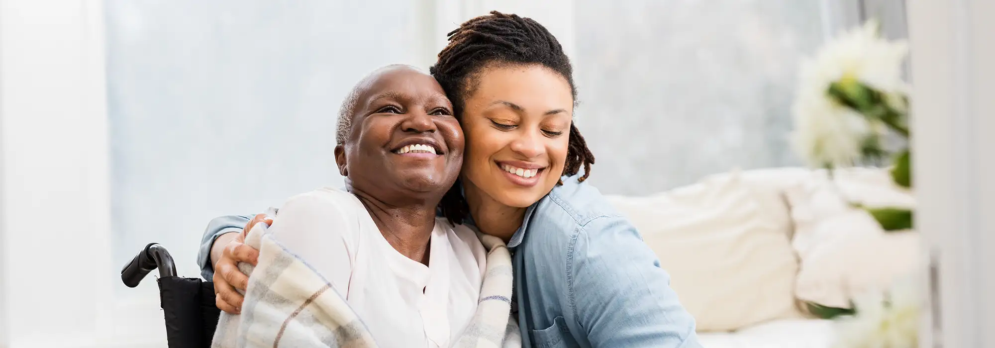Senior woman in a wheelchair with her caregiver hugging her 