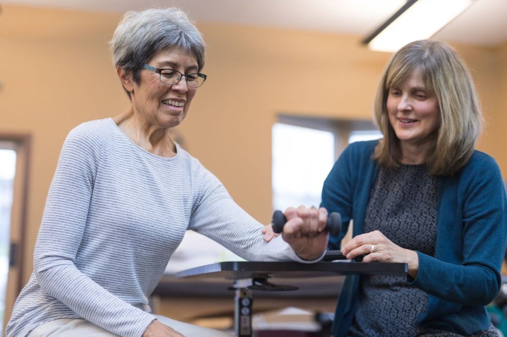 Skilled nurse doing weight training with senior woman 